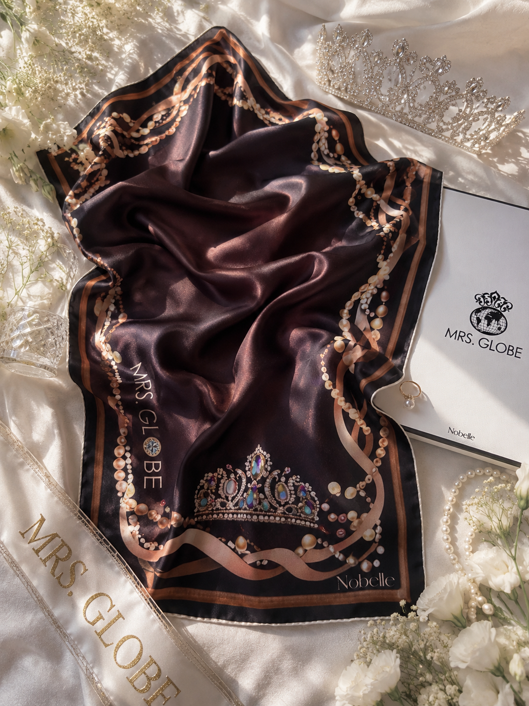 Decorative brown scarf with intricate patterns and 'MRS. GLOBE' branding on a white fabric background.